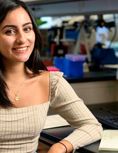 Smiling person sat at a desk with a computer